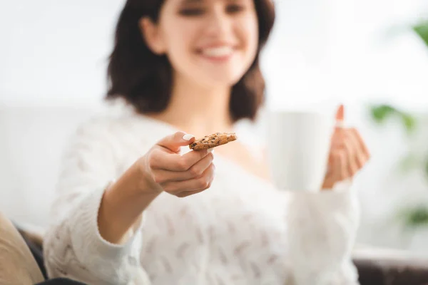 Enfoque selectivo de la chica feliz con taza de café celebración de la galleta - foto de stock