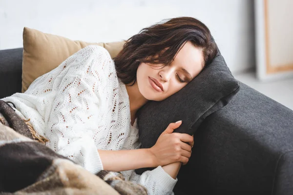 Hermosa mujer joven durmiendo en manta en el sofá - foto de stock