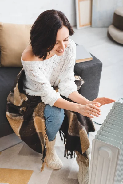 Beautiful happy young woman with blanket in cold room with heater — Stock Photo