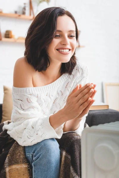 Beautiful smiling girl in cold room with heater — Stock Photo