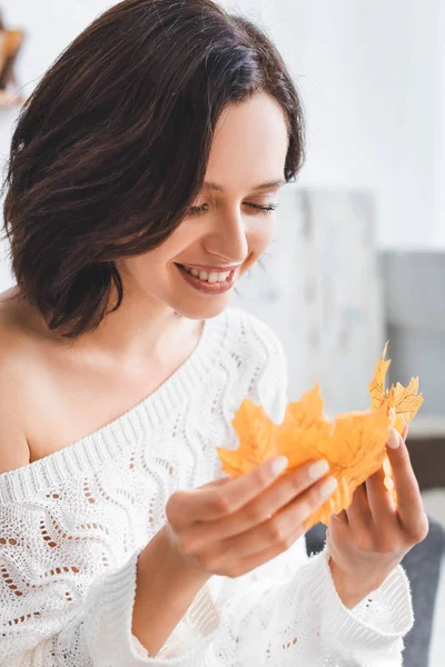 Schönes glückliches Mädchen, das gelbe Herbstblätter zu Hause betrachtet — Stockfoto