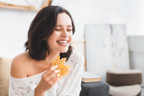 Beautiful laughing girl holding yellow autumn at home — Stock Photo