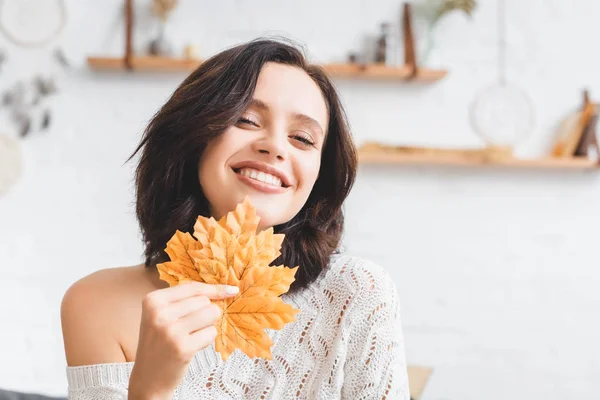 Bella donna allegra che tiene foglie di autunno gialle — Foto stock