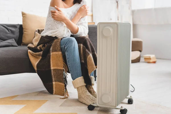 Cropped view of woman with blanket warming up with heater in cold room — Stock Photo