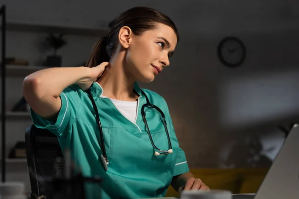 Attractive nurse in uniform having neck pain during night shift — Stock Photo