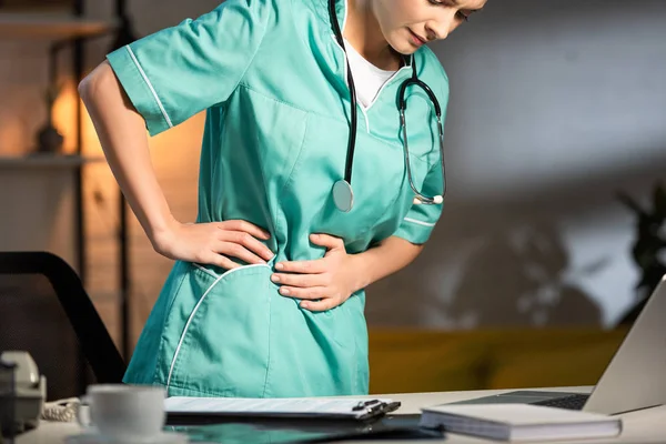 Ausgeschnittene Ansicht einer Krankenschwester in Uniform mit Rückenschmerzen während der Nachtschicht — Stockfoto