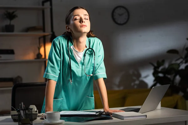 Attraente infermiera in uniforme con gli occhi chiusi durante il turno di notte — Foto stock