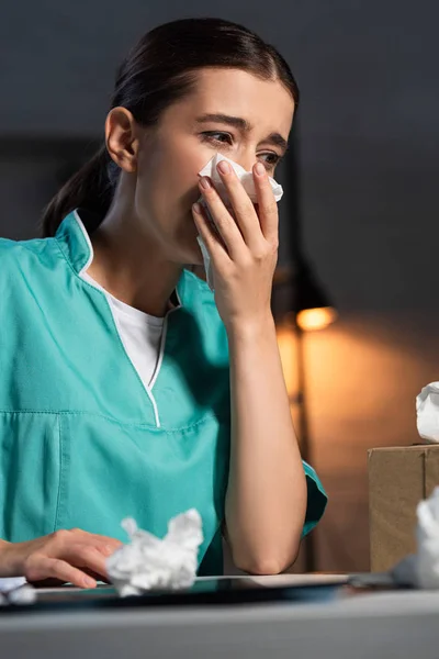 Attraktive Krankenschwester in Uniform niest und hält Serviette während der Nachtschicht — Stockfoto