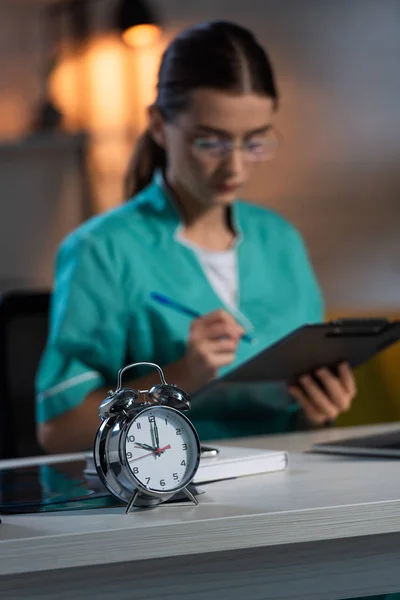 Mise au point sélective de la montre d'alarme sur la table en bois pendant le quart de nuit — Photo de stock