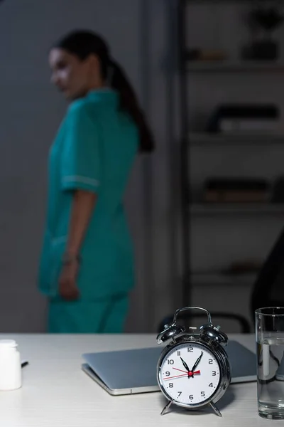 Mise au point sélective de la montre d'alarme sur la table en bois pendant le quart de nuit — Photo de stock