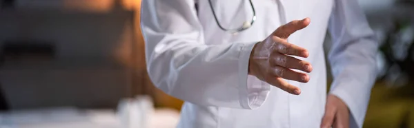 Ausgeschnittene Ansicht des Arztes im weißen Kittel mit Stethoskop mit ausgestreckten Händen während der Nachtschicht — Stockfoto