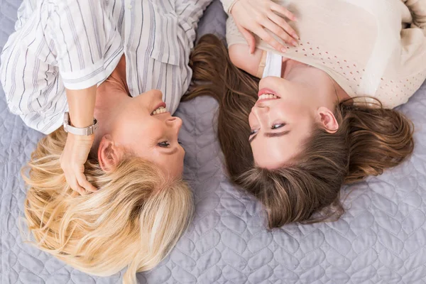 Overhead view of happy mother and daughter talking while lying on bed — Stock Photo