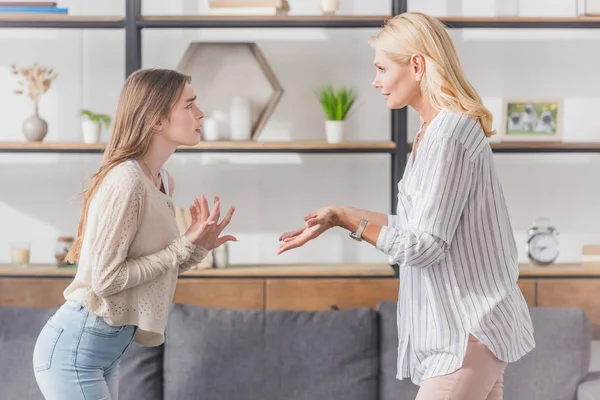 Side view of mother and daughter quarreling while standing in living room — Stock Photo