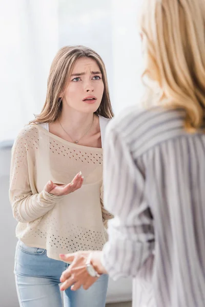 Rückansicht von reifer Frau und kleiner Tochter, die sich streiten und Fragegegestellung zeigen — Stockfoto