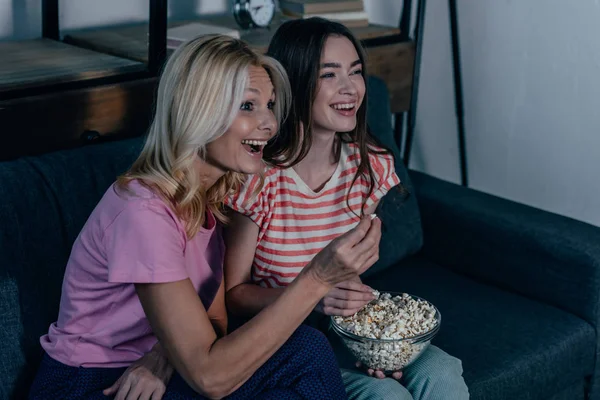 Exticed mother and daughter watching tv and eating popcorn — Stock Photo