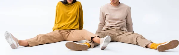 Panoramic shot of man and woman sitting on white — Stock Photo