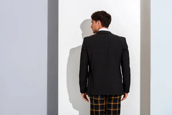 Elegante uomo in pantaloni a quadretti in piedi su bianco e grigio — Foto stock