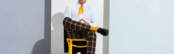 Panoramic shot of man posing while sitting on white and grey — Stock Photo