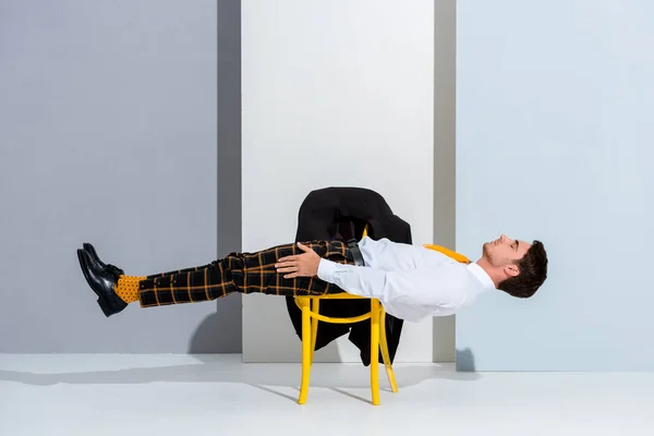Homem posando enquanto deitado na cadeira amarela em branco e cinza — Fotografia de Stock