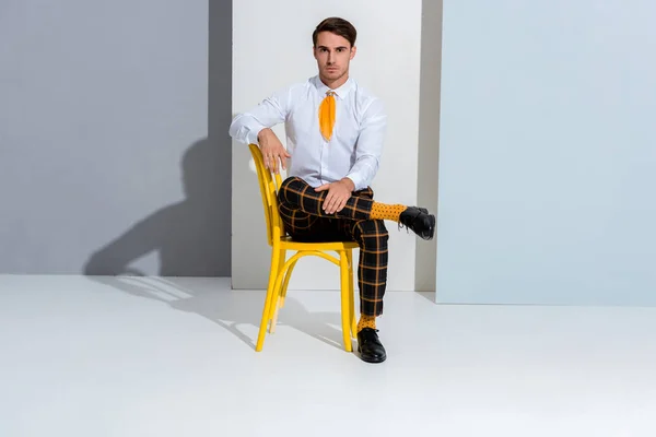 Positive man in plaid trousers sitting on white and grey — Stock Photo