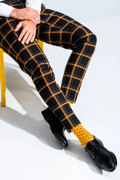 Vista ritagliata dell'uomo in calzini punteggiati gialli seduto sulla sedia su bianco — Foto stock