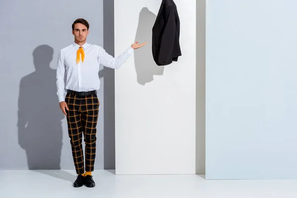 Handsome man in plaid trousers standing and gesturing on white and grey — Stock Photo