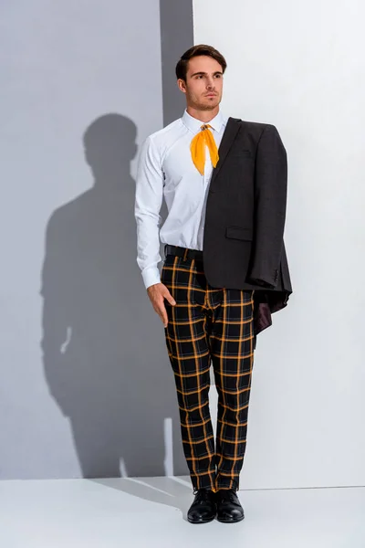Hombre guapo en pantalones a cuadros de pie en blanco y gris - foto de stock