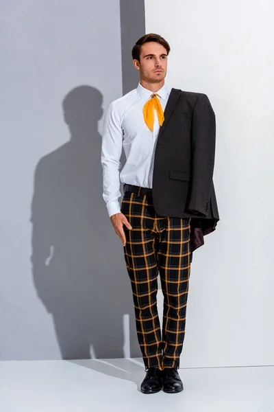 Handsome man in plaid trousers standing on white and grey — Stock Photo