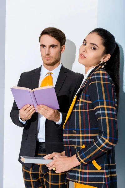 Attraktives Mädchen mit Buch in der Nähe von stilvollem Mann auf Weiß — Stockfoto