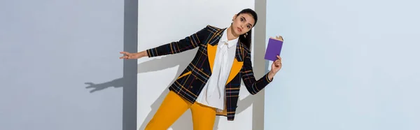 Panoramic shot of woman holding purple book on white and grey — Stock Photo