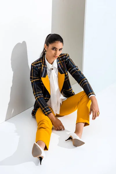 Young and trendy woman looking at camera while sitting on grey and white — Stock Photo