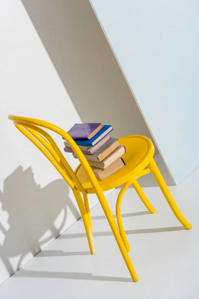 Yellow chair with books on grey and white — Stock Photo