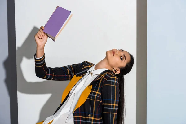 Mulher atraente segurando livro roxo em cinza e branco — Fotografia de Stock