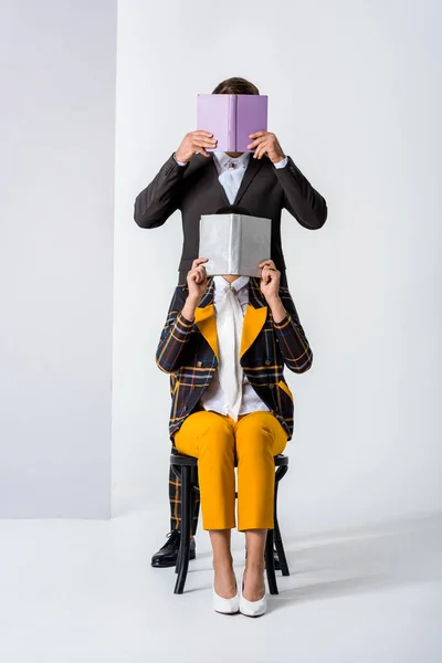 Homem elegante e mulher cobrindo rostos enquanto segurando livros em branco — Fotografia de Stock