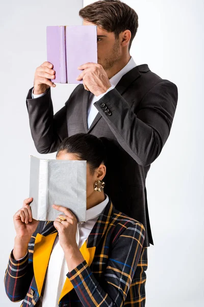 Uomo e donna alla moda che coprono i volti mentre tengono libri su bianco — Foto stock