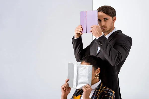 L'uomo elegante che tiene il libro vicino a donna su bianco — Foto stock