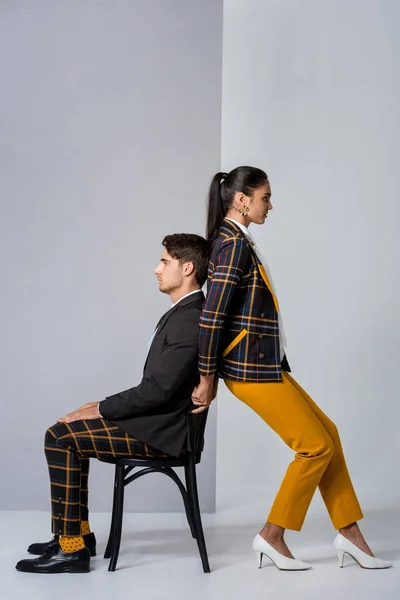 Side view of woman standing near man sitting on chair on white — Stock Photo