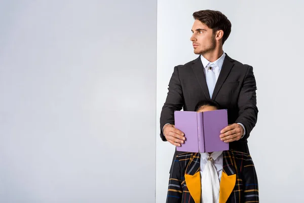 Handsome man covering face of girl while holding book on white — Stock Photo