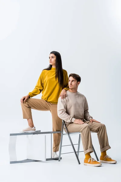 Schönes Mädchen steht in der Nähe auf Stuhl und schöner Mann isoliert auf weiß — Stockfoto