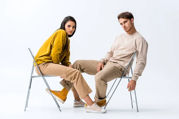 Belle femme assise sur une chaise près de bel homme sur blanc — Photo de stock