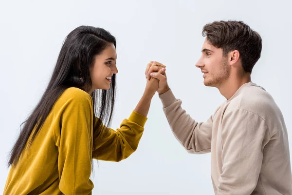 Vista laterale di bell'uomo e felice donna che tiene le mani isolate su bianco — Foto stock