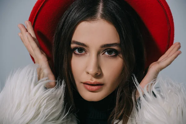 Élégante femme élégante posant en manteau de fourrure blanc et chapeau rouge, isolé sur gris — Photo de stock