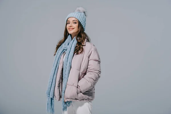 Belle femme heureuse posant en manteau chaud, bonnet tricoté et écharpe, isolée sur gris — Photo de stock