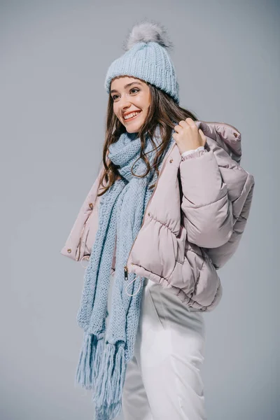 Ragazza sorridente posa in cappotto caldo, cappello e sciarpa lavorati a maglia, isolato su grigio — Foto stock