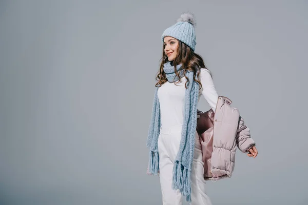 Beautiful happy girl posing in coat, knitted hat and scarf, isolated on grey — Stock Photo