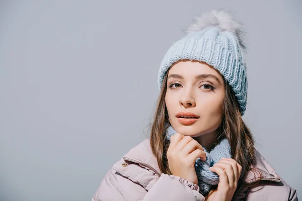 Belle fille coûteuse posant en manteau, bonnet tricoté et écharpe, isolé sur gris — Photo de stock