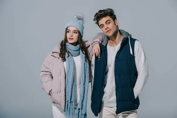 Stylish young couple posing in winter outfit, isolated on grey — Stock Photo