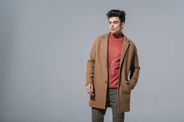 Fashionable man posing in beige coat, isolated on grey — Stock Photo