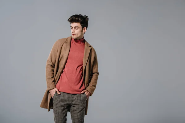 Fashionable man posing in autumn coat, isolated on grey — Stock Photo