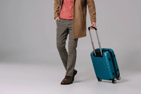 Обрезанный вид человека, позирующего с багажом для путешествий на сером — стоковое фото